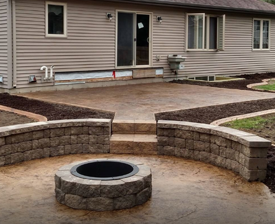 Red colored stamped concrete patio with two steps down leading to fire pit area with retaining wall